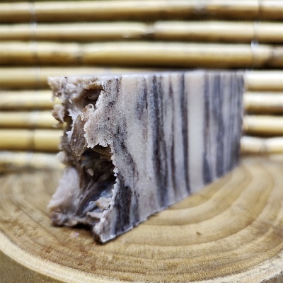 Barra de sabão marmoreada em tons castanhos sobre base de madeira