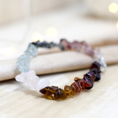 Pulseira elástica com pedras semipreciosas coloridas sobre superfície de madeira