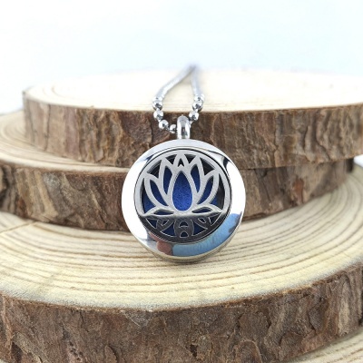 Colar pendente redondo com flor de lótus em aço inoxidável e fundo azul sobre madeira