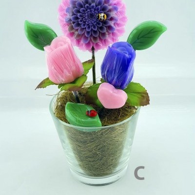 Vaso de vidro com flores artificiais coloridas e folhas verdes