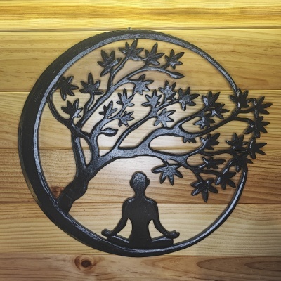 Objeto decorativo circular em metal preto com figura de pessoa e árvore