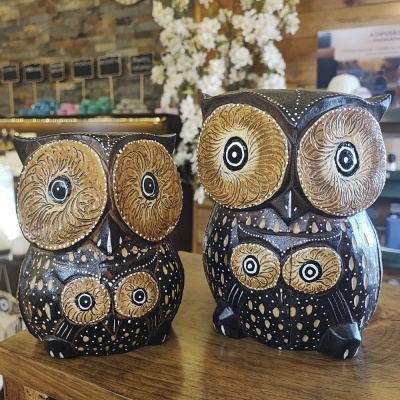Duas corujas decorativas de cerâmica castanha e preta sobre madeira