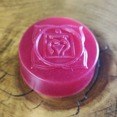 Plaqueta circular vermelha gravada em relevo sobre fundo de madeira