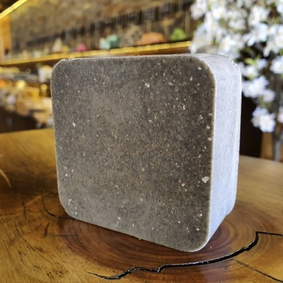 Bloco cinza quadrado de textura rugosa sobre madeira natural