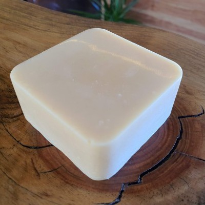 Sabonete quadrado creme sobre superfície de madeira com veios