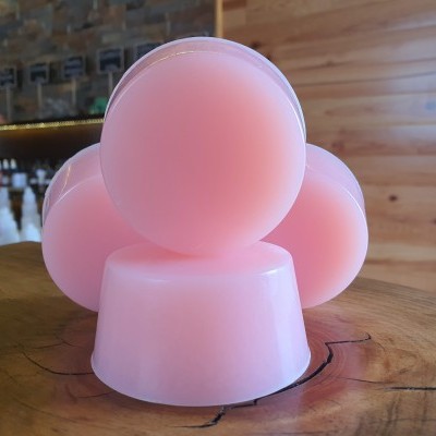 Sabonetes redondos rosa empilhados em madeira rústica com fundo de madeira clara