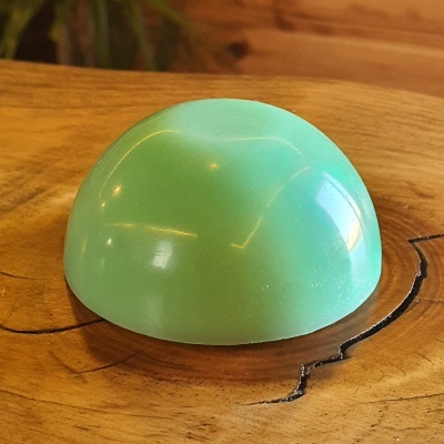 Objeto verde semiesférico sobre madeira clara