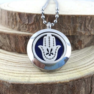 Colar com pendente de mão de Hamsá em metal prateado com fundo azul sobre tronco de árvore