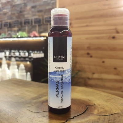 Frasco de óleo de massagem VALENTINA com rótulo branco e azul em superfície de madeira