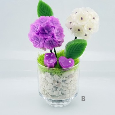 Arranjo decorativo artificial em copo de vidro com flores e ornamentos roxos