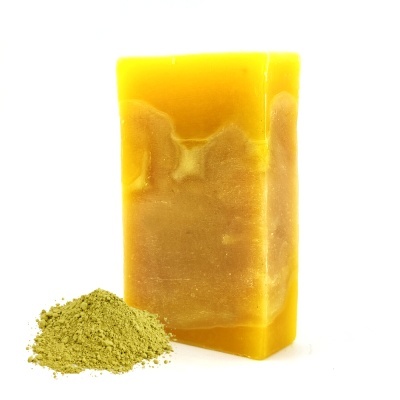 Sabonete sólido amarelo e castanho ao lado de pó verde claro