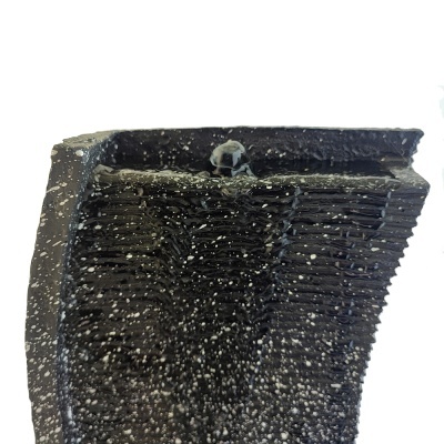 Fragmento de peça preta com textura rugosa e padrão de linhas horizontais