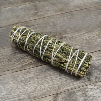 Vara de ervas amarrada com fio branco sobre madeira