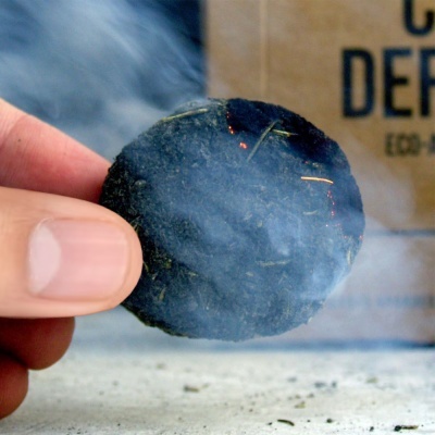 Disco preto queimando na mão com fumo e saco castanho ao fundo