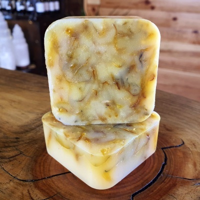 Dois sabonetes quadrados amarelos claros e bege com textura marmoreada em madeira