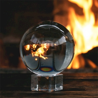 Esfera de vidro transparente sobre base de vidro com chama ao fundo