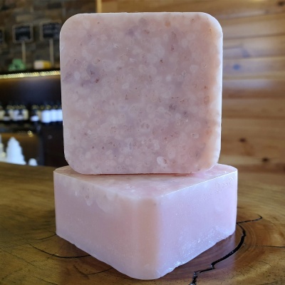 Dois sabonetes quadrados cor-de-rosa empilhados sobre madeira com fundo de prateleiras