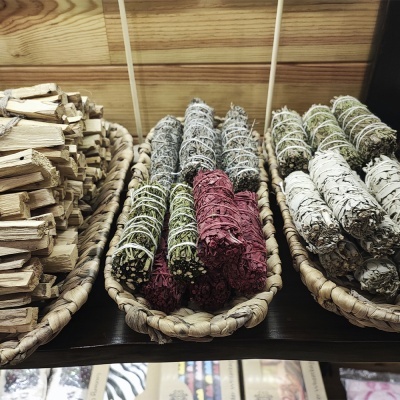 Bastões de ervas para queima em três cestos de vime sobre mesa de madeira