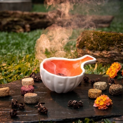 Taça branca com interior laranja e bolos coloridos sobre tábua de madeira em ambiente exterior