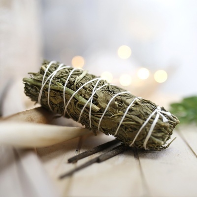 Varetas de incenso e feixe de folhas secas amarradas em madeira clara