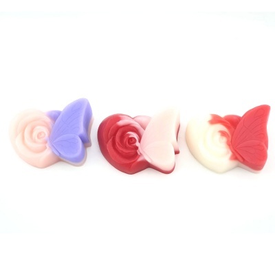 Três sabonetes decorativos em forma de rosa com borboletas de cores diferentes sobre fundo branco.