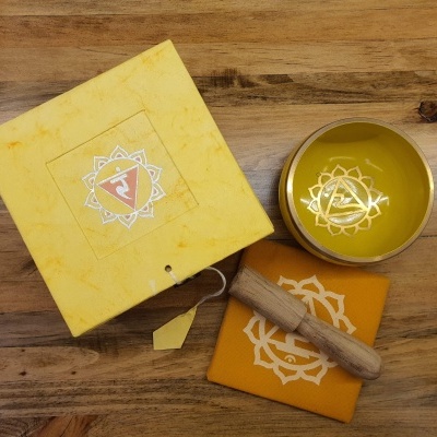 Conjunto de taça tibetana dourada, maço de madeira, pano e caixa amarela com símbolos