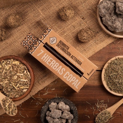 Caixa de bombita com carvão e ervas secas em tigelas sobre madeira e tecido saco