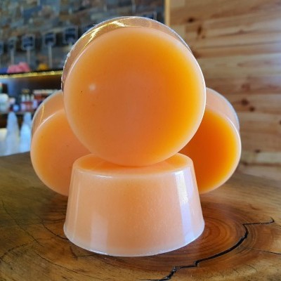 Conjunto de sabonetes laranja claro empilhados sobre mesa de madeira rústica