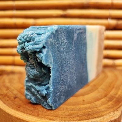 Barra de sabão artesanal azul e branca com textura rústica em superfície de madeira