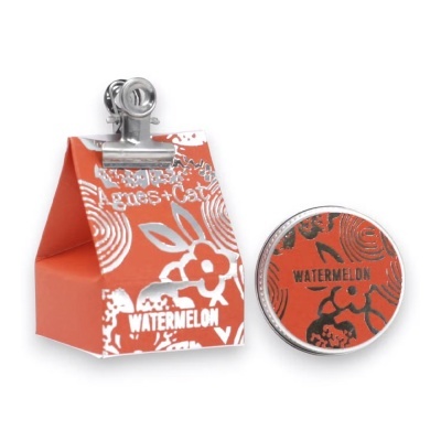 Conjunto embalagem e lata pequenas vermelhas com padrão floral e texto Agnes+Cat e WATERMELON.