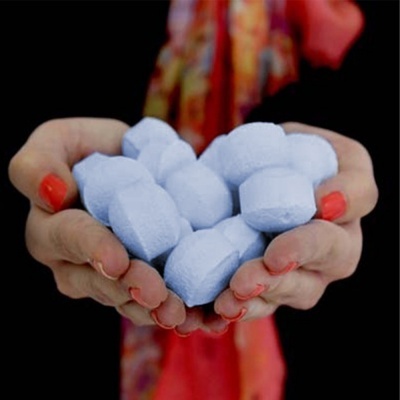 Mãos segurando pedras de gelo azuis contra fundo negro