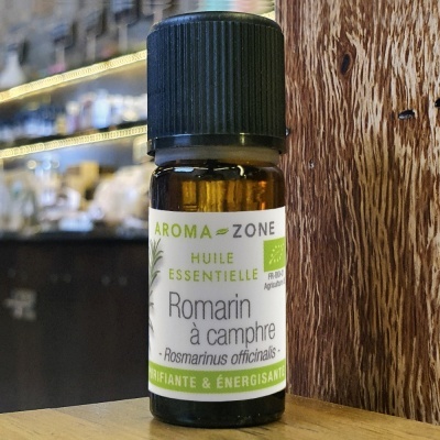 Frasco de óleo essencial Aroma-Zone Romarin à camphre em superfície de madeira