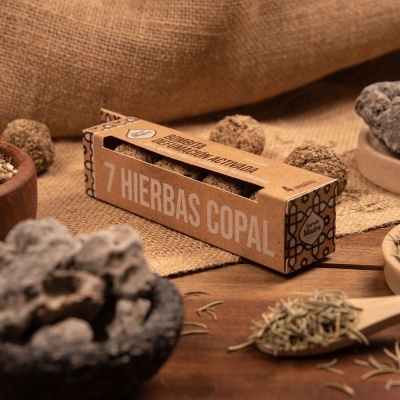Caixa de 7 Hierbas Copal com pedras de copal e ervas secas em superfície de madeira e tecido.