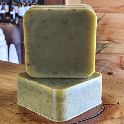 Dois sabonetes quadrados verdes com textura granulada sobre madeira