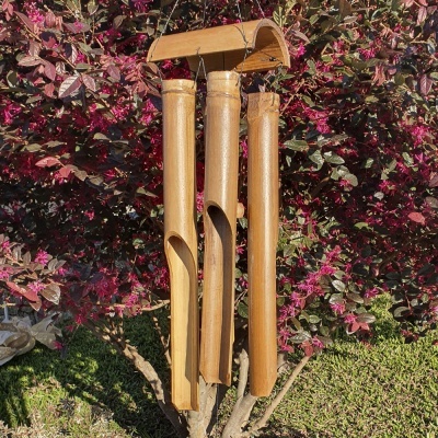 Sino de vento de bambu pendurado em arbusto com folhas vermelhas