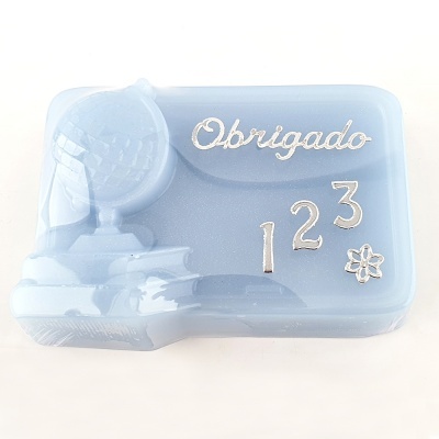Sabonete azul claro com globo, livro e texto Obrigado em branco