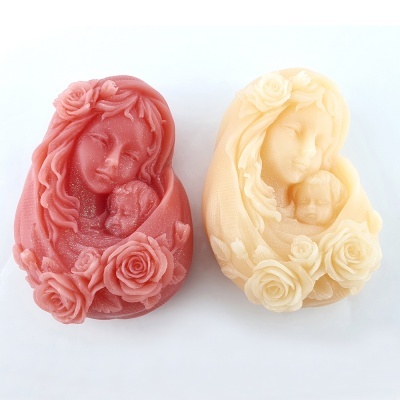 Sabonetes esculpidos em forma de mãe com bebé, um rosa e outro creme, com flores decorativas.