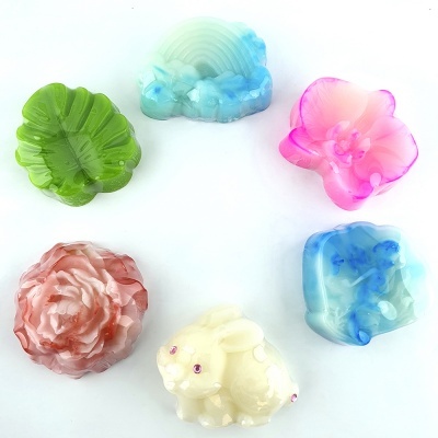 Seis sabonetes artesanais coloridos em formatos variados sobre fundo branco