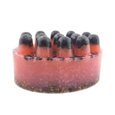 Sabonete artesanal oval rosa com pontos pretos e base translúcida