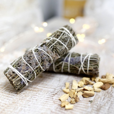 Feixes de ervas secas amarrados com corda branca sobre mesa de madeira clara