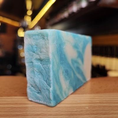Barra de sabonete azul e branco marmoreada sobre bancada de madeira