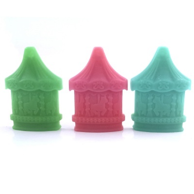 Três carrosséis pequenos coloridos em verde, rosa e azul com detalhes de cavalos em relevo.