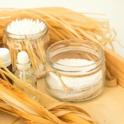 Frascos de vidro com algodão, palitos de madeira e líquido numa caixa de madeira com folhas secas