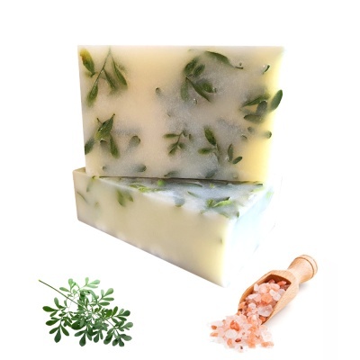 Sabonetes artesanais com folhas verdes, sal grosso rosa em espátula e ramo de folhas verdes