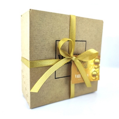 Caixa de presente castanha com laço amarelo e etiqueta dourada