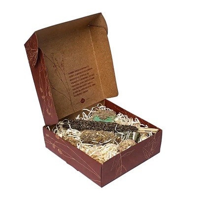 Caixa de cartão castanha aberta com saco de papel, espigas secas e palha