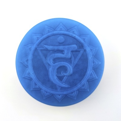 Sabonete redondo azul com símbolo de chakra em relevo azul mais escuro.