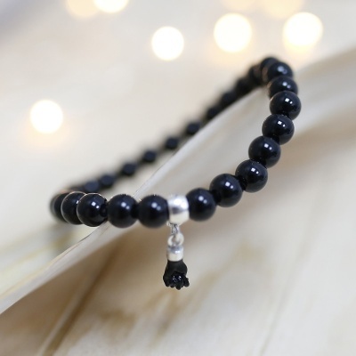 Pulseira de contas pretas com pendente em forma de borla