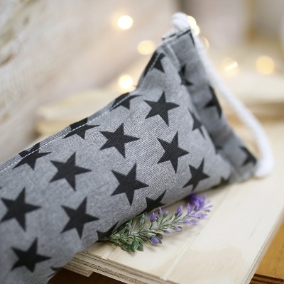 Porta-óculos cinzento com estrelas pretas sobre livro com flor de lavanda