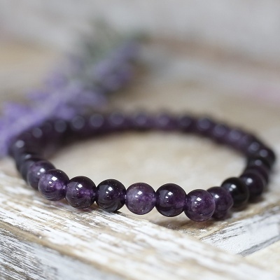 Pulseira de contas roxas sobre superfície de madeira clara